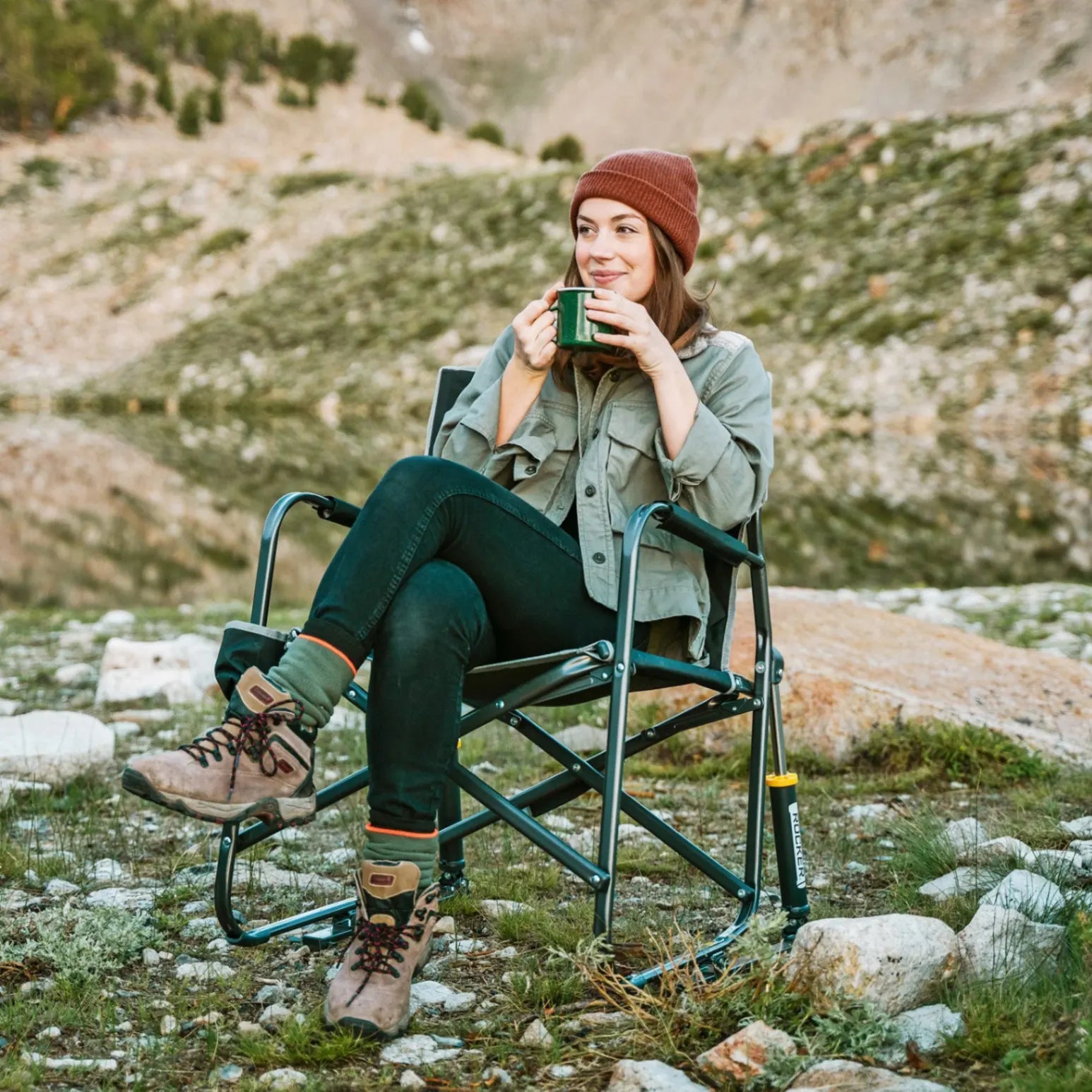 A woman in a beanie sipping coffee while sitting in a black Freestyle Rocker.