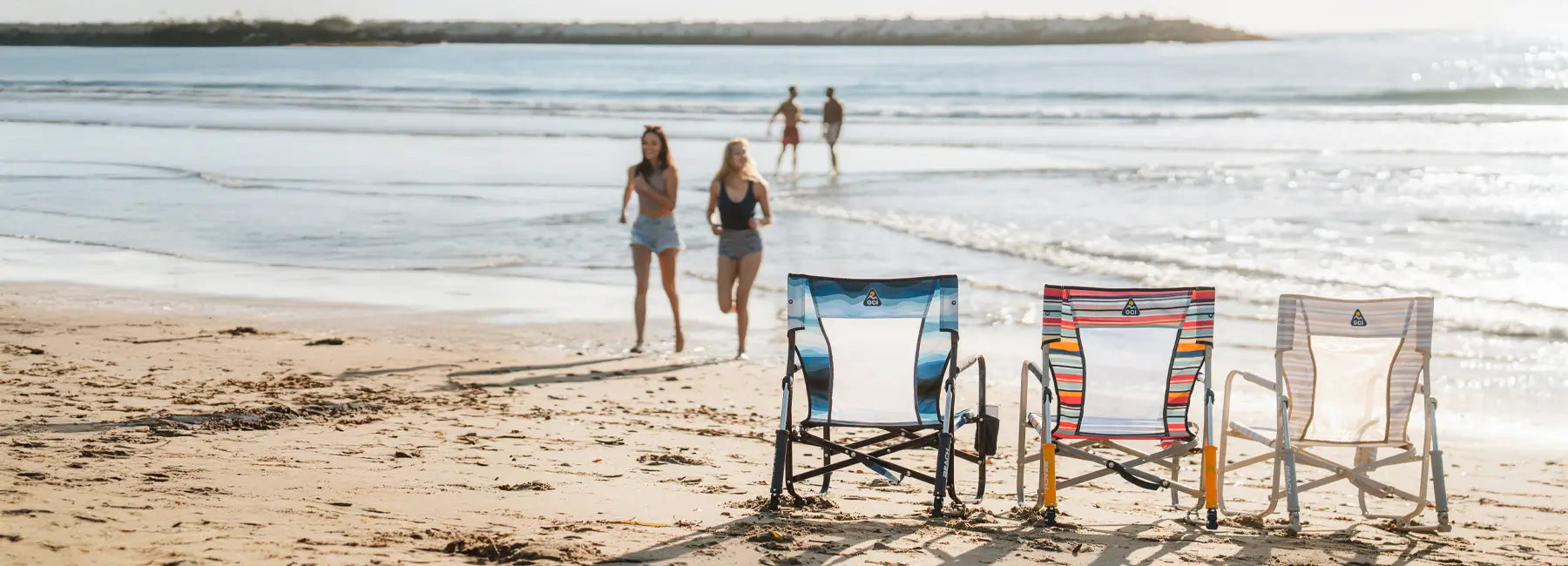 Three beach rockers positioned on the beach facing towards the ocean.