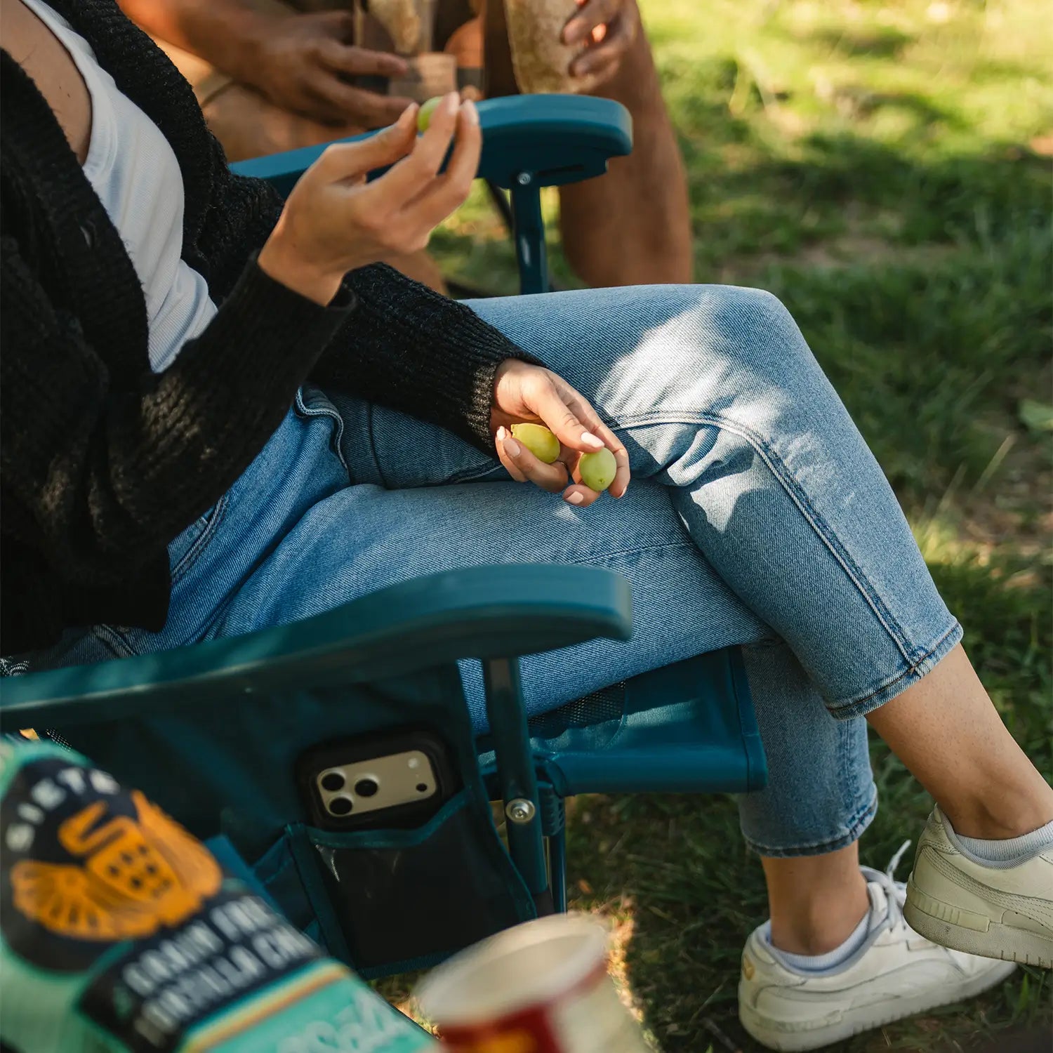 A woman holding grapes as she rocks in the teal BreezeRocker.