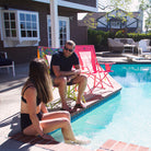 Man and woman relaxing poolside, man seated in blush Comfort Pro Rocker with floral version beside him.