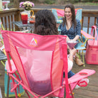 Woman seated in blush Comfort Pro Rocker on a deck, chatting with a friend in a colorful rocker.