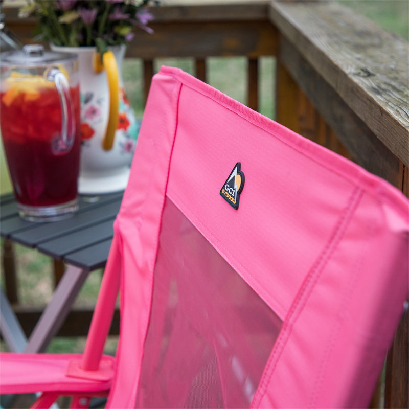 Close-up of blush Comfort Pro Rocker backrest with GCI Outdoor logo, next to a table with floral pitcher.