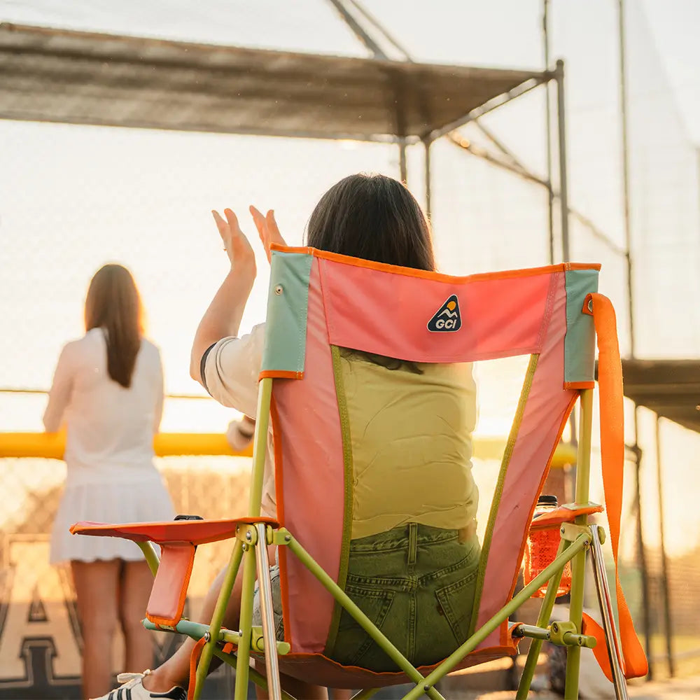 A woman sitting in a sweet tea comfort pro rocker cheering on a stadium game.