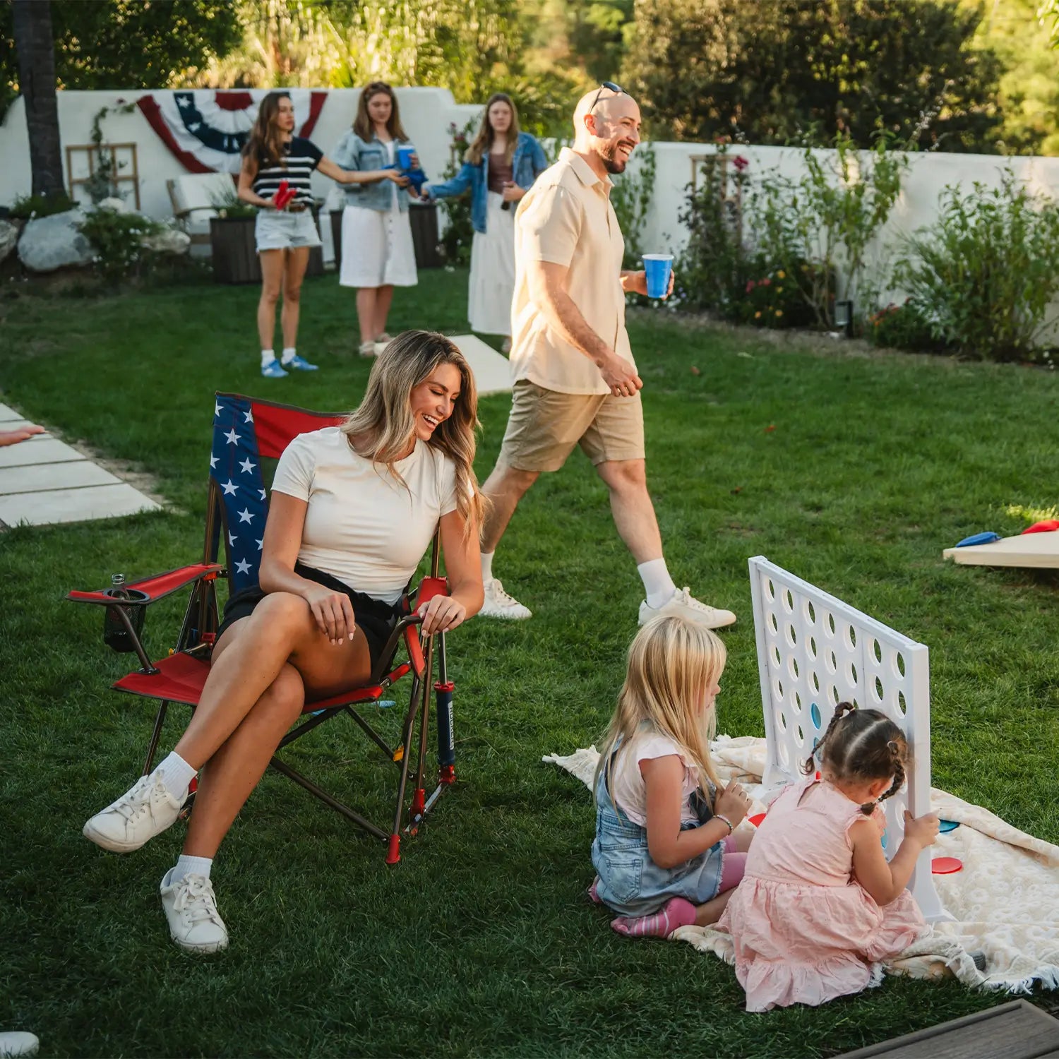 A woman sitting in a USA Comfort Pro Rocker while watching children play connect four.