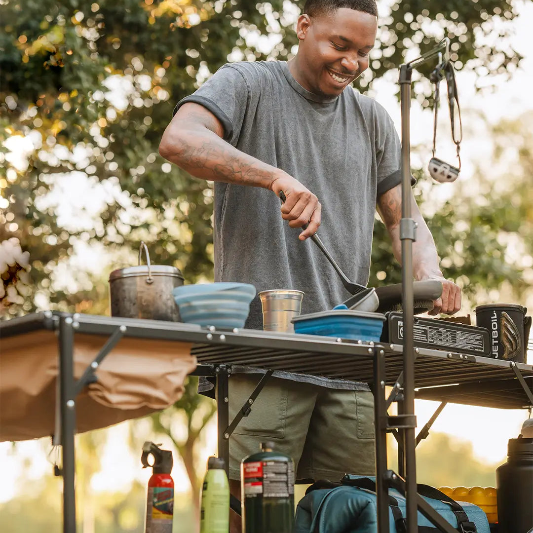 A man cooking food using a GCI Outdoor cook station.