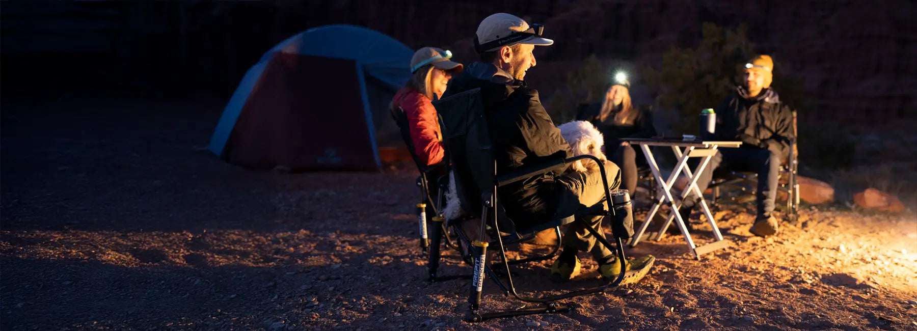 Group of people gathered around a campfire while sitting in firepit rockers.