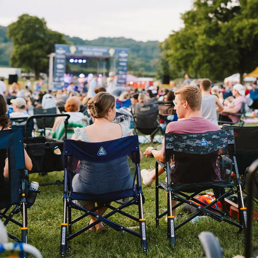Two concert goers sitting in freestyle rocker elite chairs at a venue.