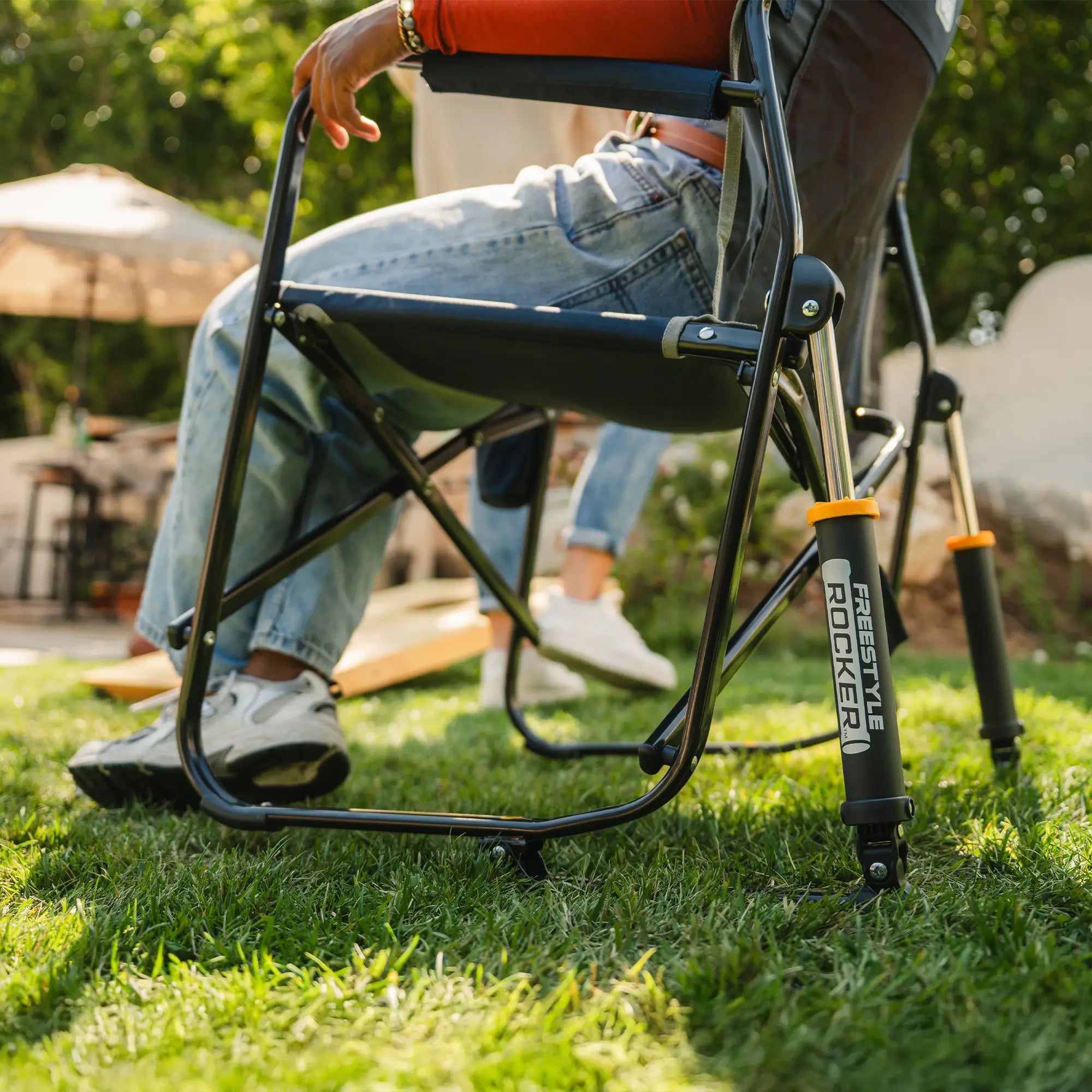 A low angle of the indigo freestyle rocker showing the spring action rocking technology while a woman sits in the chair.