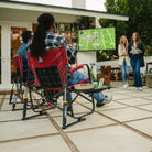 Two people cheering while watching a football game in their freestyle rocker xl with side table chairs.