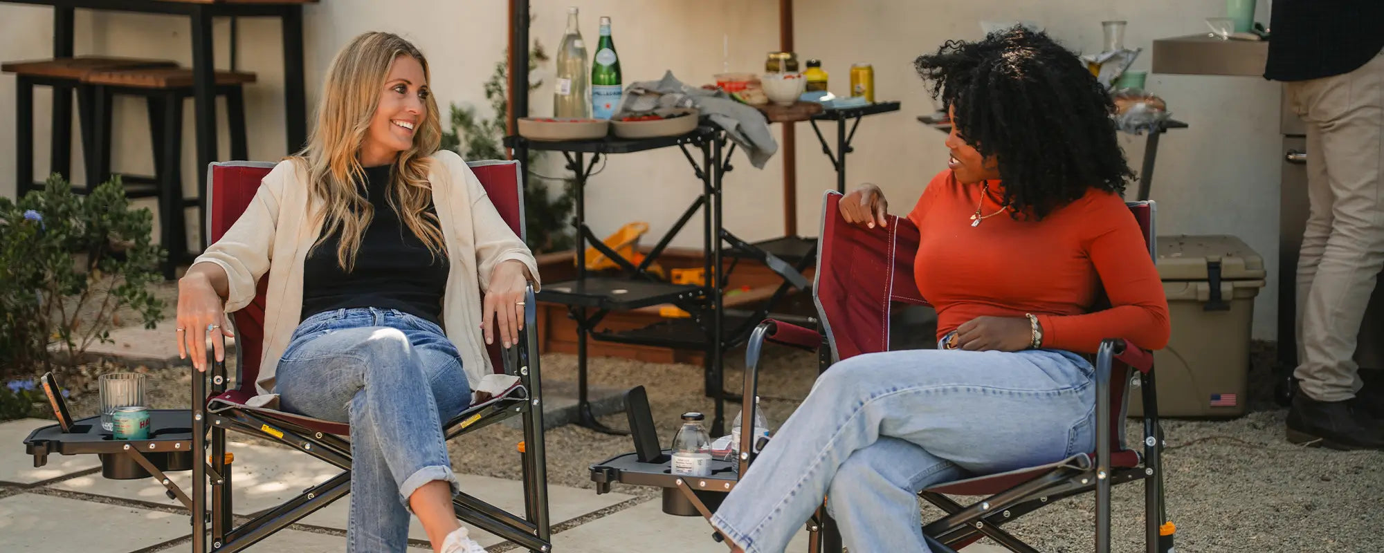 Two women conversing in their cinnamon freestyle rockers with side tables.