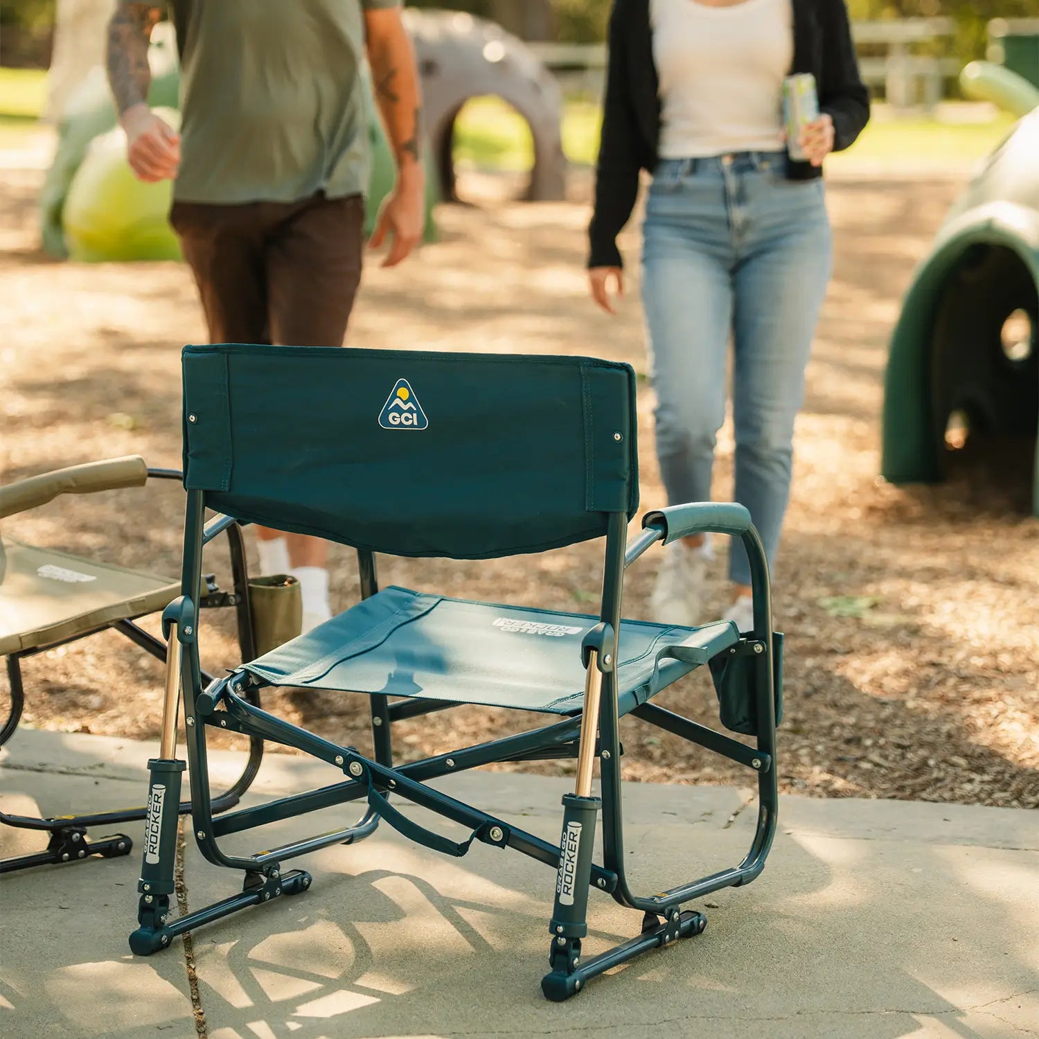 Two people walking away from a playground as they approach two opened Grab and Go Rockers.