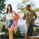 Woman carries a Soft Pink Leaf Kickback Rocker while smiling and walking with a man outdoors.