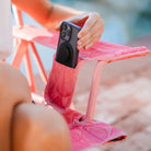 Close-up of a phone being placed into the arm pocket of a Soft Pink Leaf Kickback Rocker chair.
