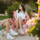 Woman sits comfortably in a Soft Pink Leaf Kickback Rocker surrounded by snacks and drinks.