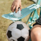 Close-up of a hand placing a drink into the cupholder of a pastel green leaf Kickback Rocker chair.