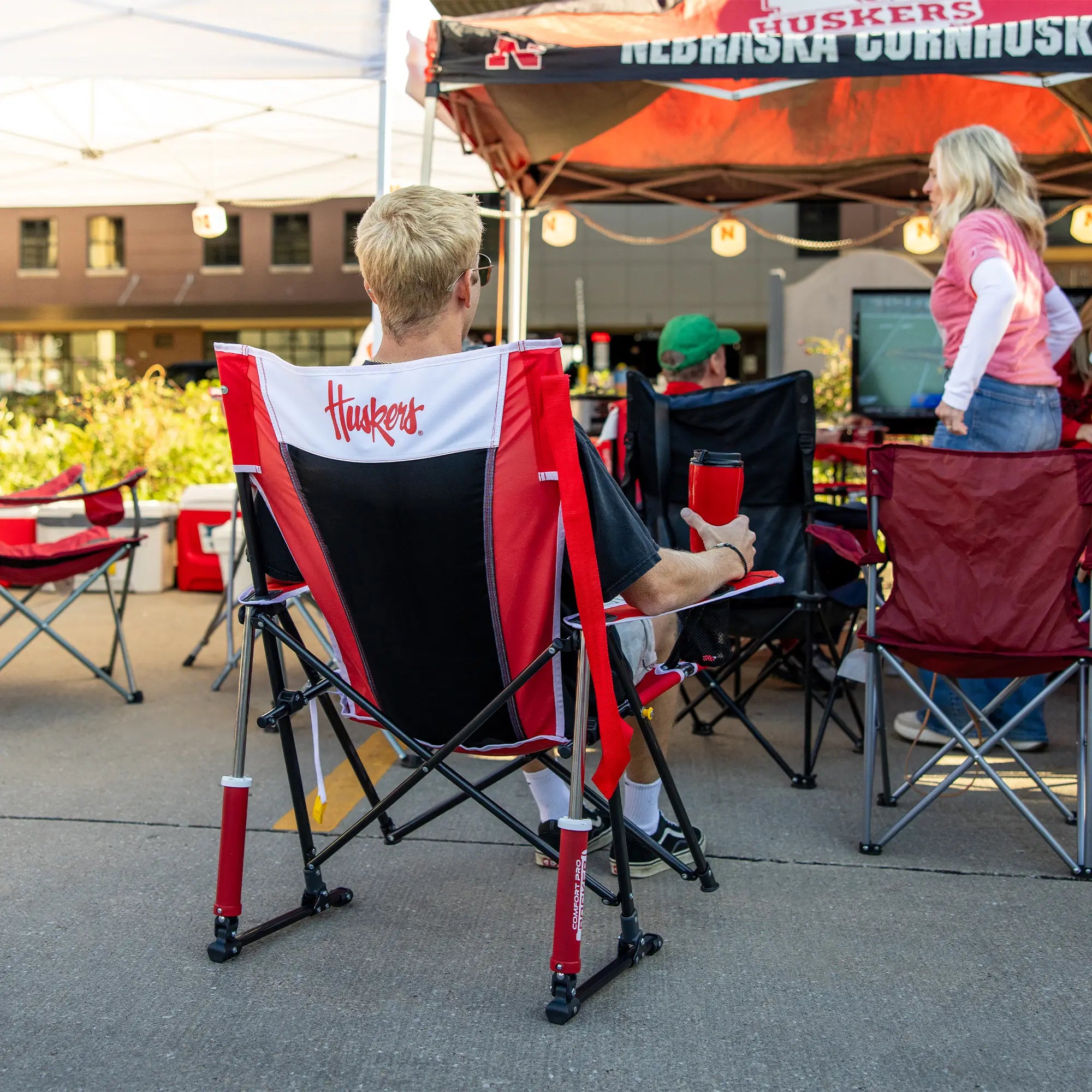 A man watching a football game on tv while sitting in a nebrask huskers comfort pro rocker.