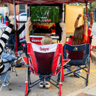 A group of tailgaters raising their arms cheering while watching a football game on tv.