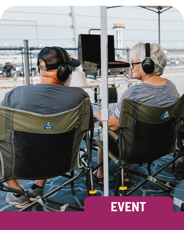 Two people sitting in outdoor rocking chairs with headphones at an event. Labelled 'Event'