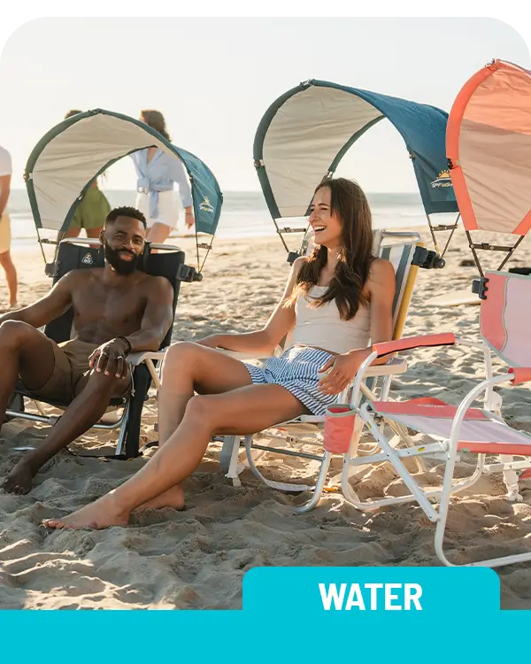 A group of beach goers sitting in several different GCI Outdoor beach chairs in the sand.