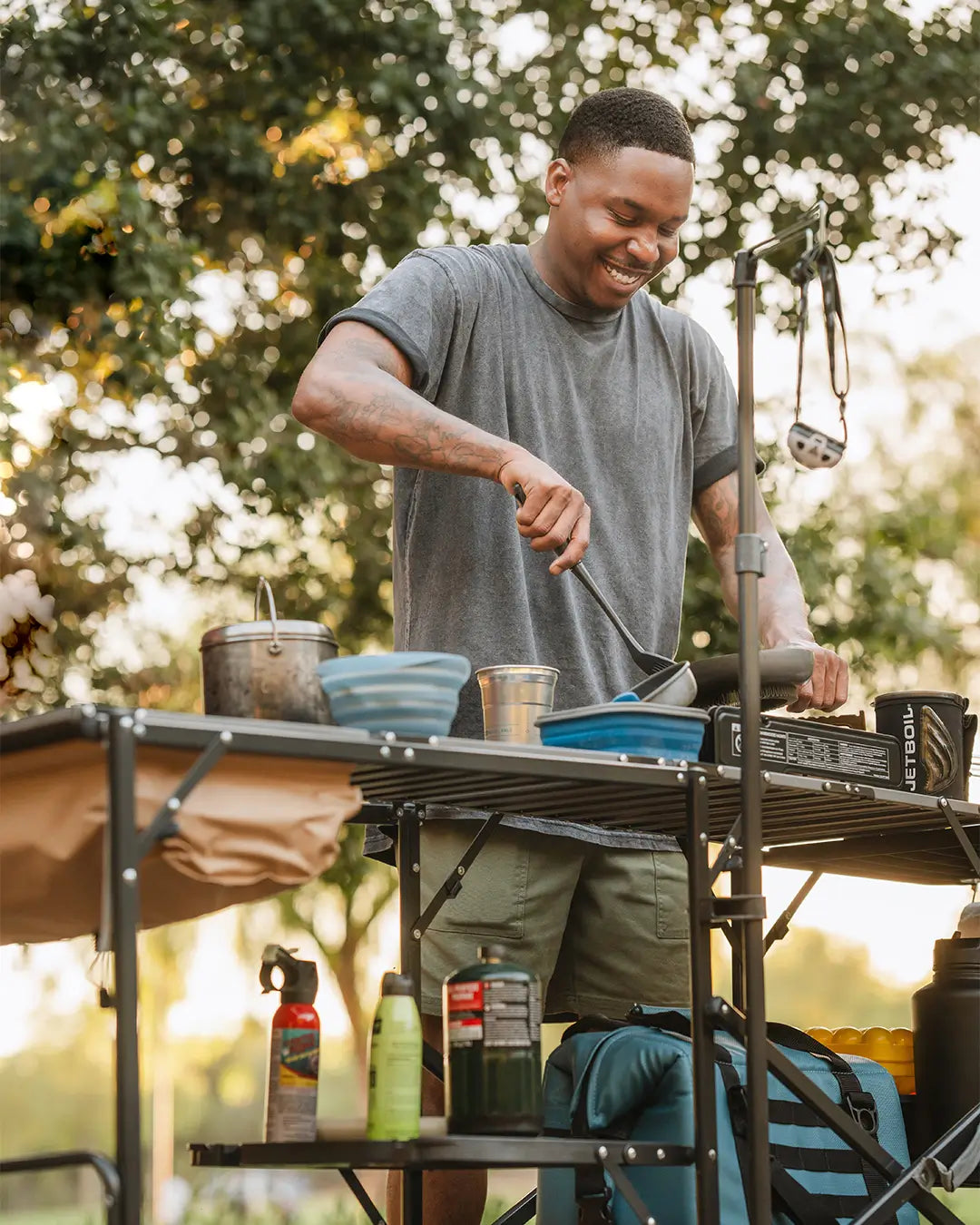 A man flipping his food in a pan while cooking on a slim-fold cook station.