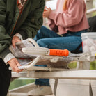 Woman folds the Snow Camo Stadium Rock-Cliner on bleacher seat.
