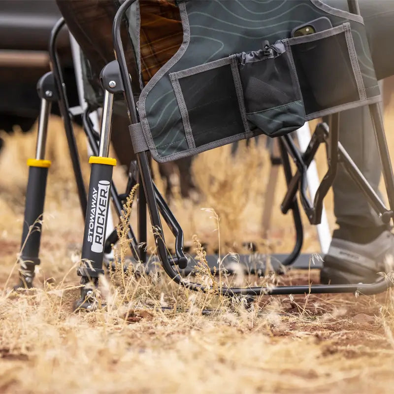Close-up of the hunter topo Stowaway Rocker’s storage pockets and rocking mechanism on dry grass.