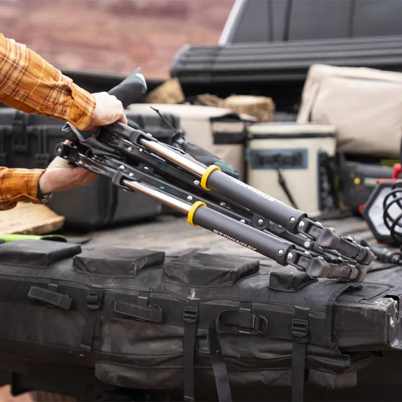 Person placing a folded hunter topo Stowaway Rocker on a truck bed with outdoor gear.