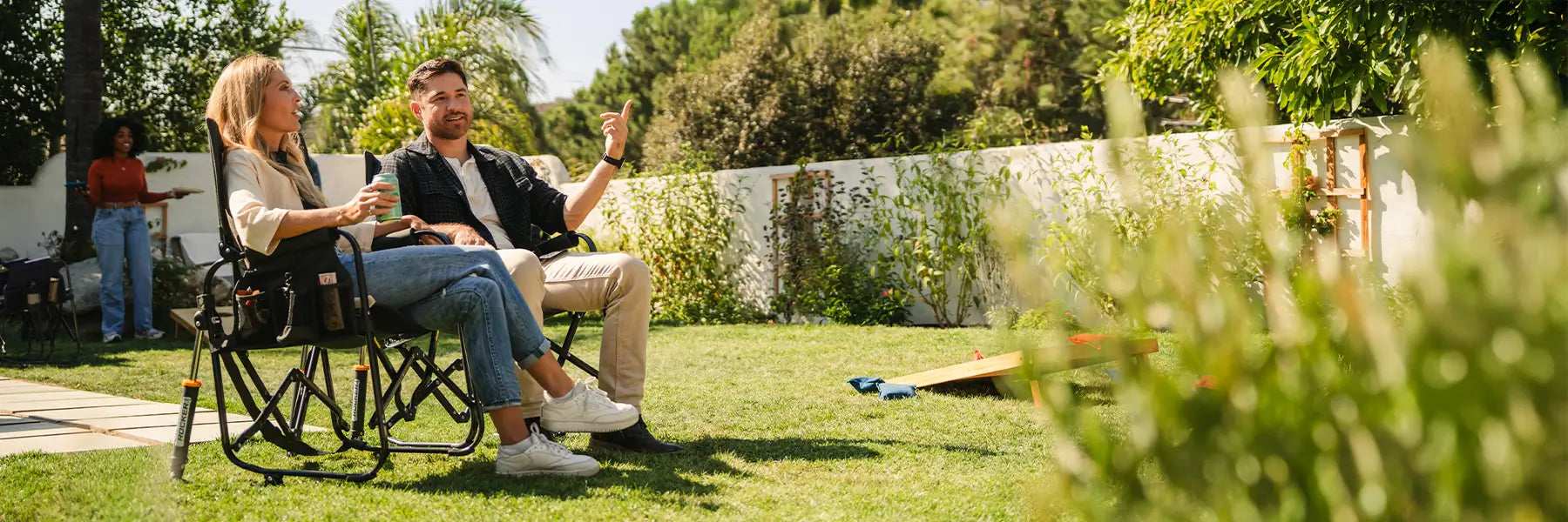 Two people sitting in a backyard in their black stowaway rocker chairs.