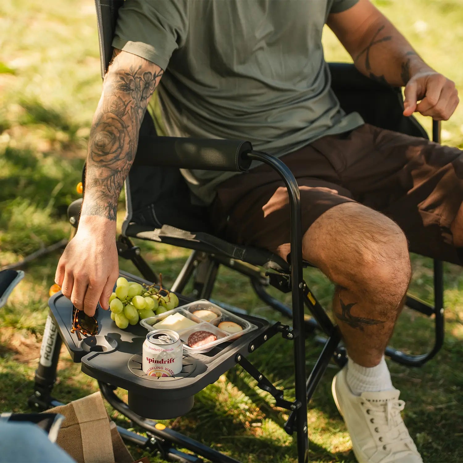A man reaching for his sunglasses that are positioned on top of the attached side table on his Stowaway Rocker with Side Table.