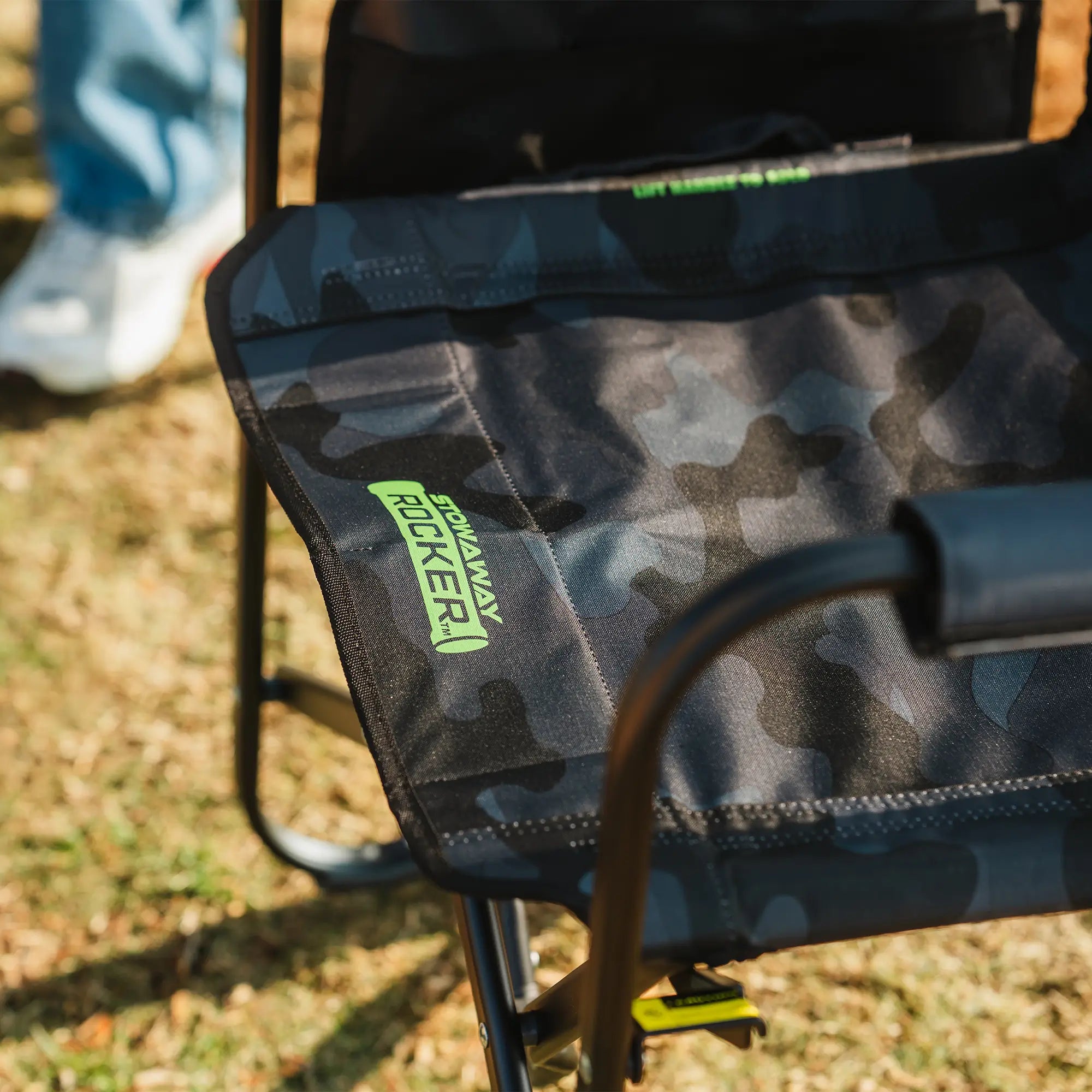 Close-up of the stealth camo Stowaway Rocker seat with a visible "Stowaway Rocker" logo in green.