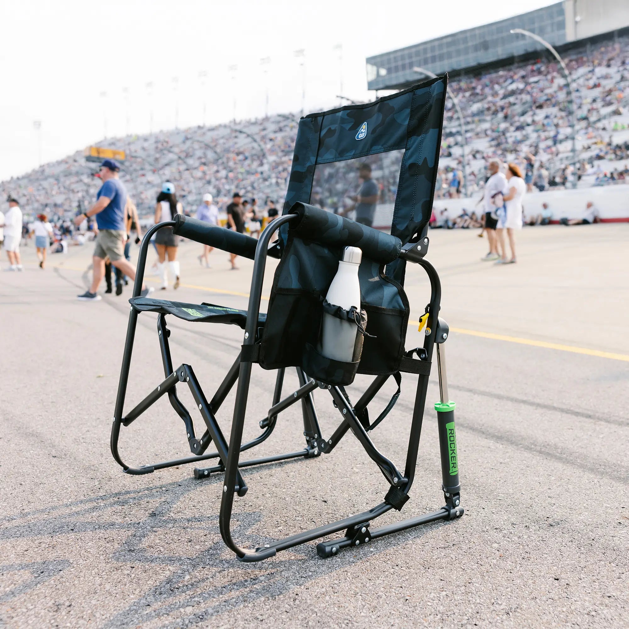 A stealth camo Stowaway Rocker positioned on a racetrack in front of a seated audience.