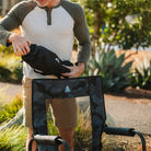 Man unpacks black sunshade accessory next to a camo GCI outdoor chair.