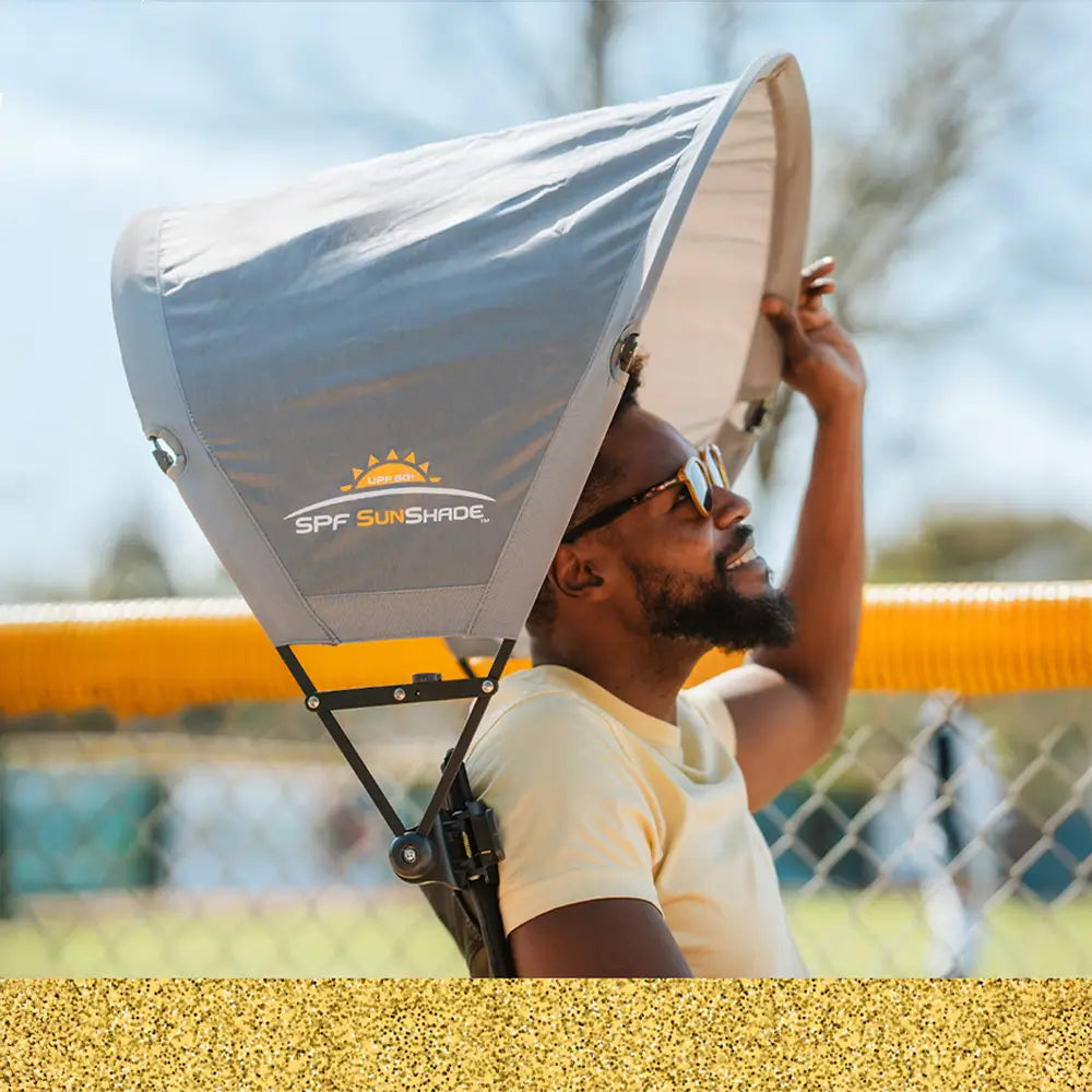 A man sitting in a GCI Outdoor chair positioning his sunshade accessory attached to the chair.