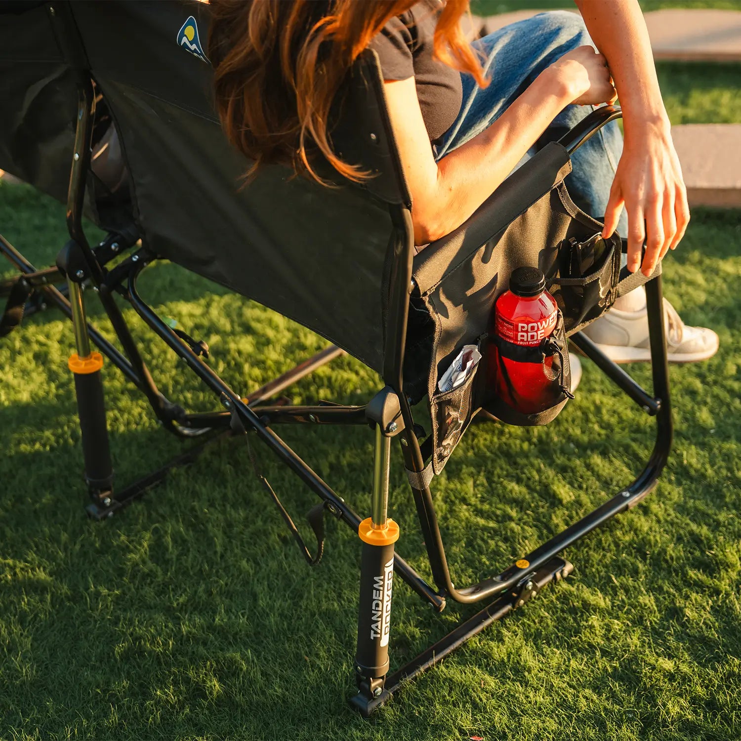 A person reaching for a Powerade drink that is sitting in the integrated side caddy.