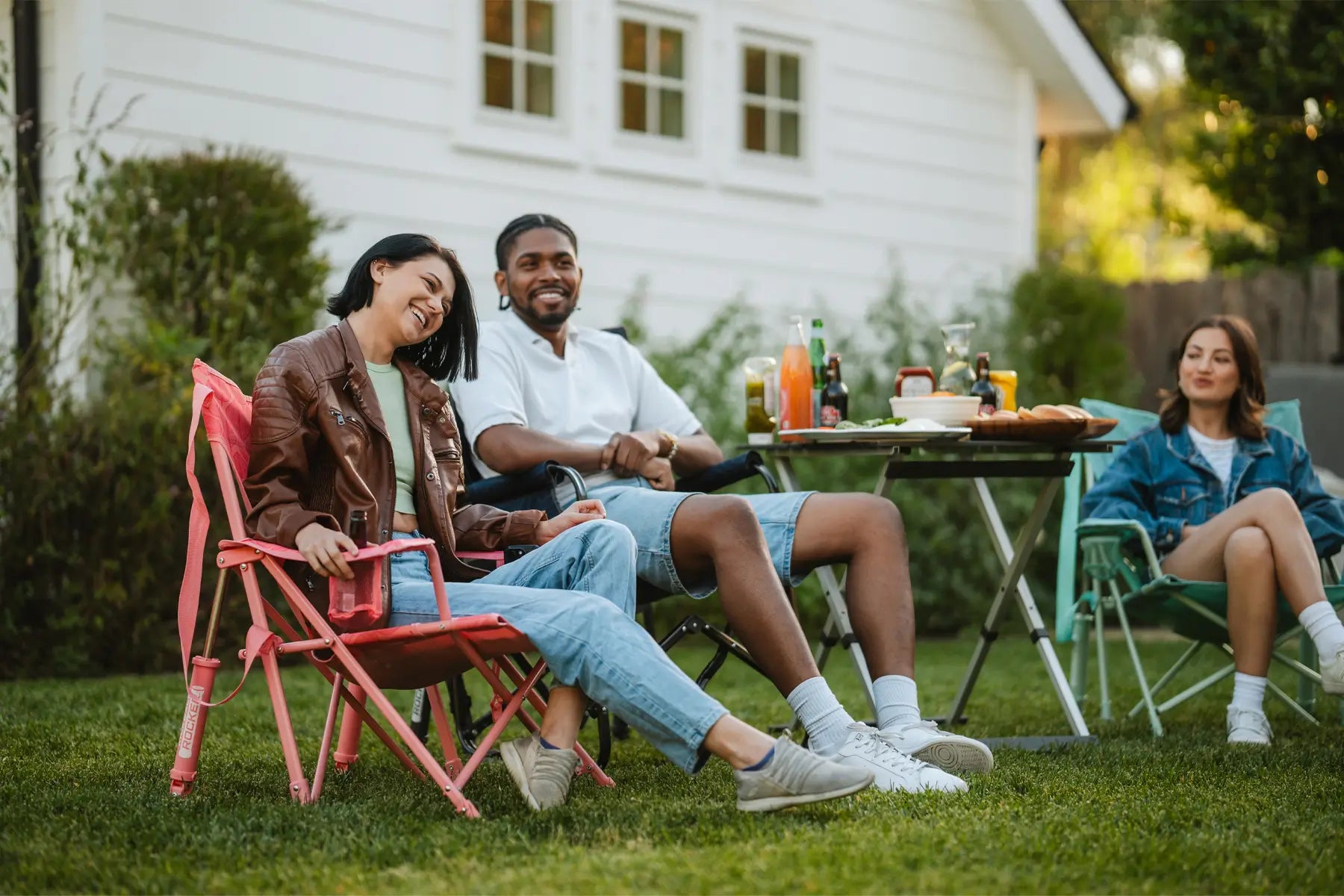 Group of people smiling and laughing while sitting in backyard.