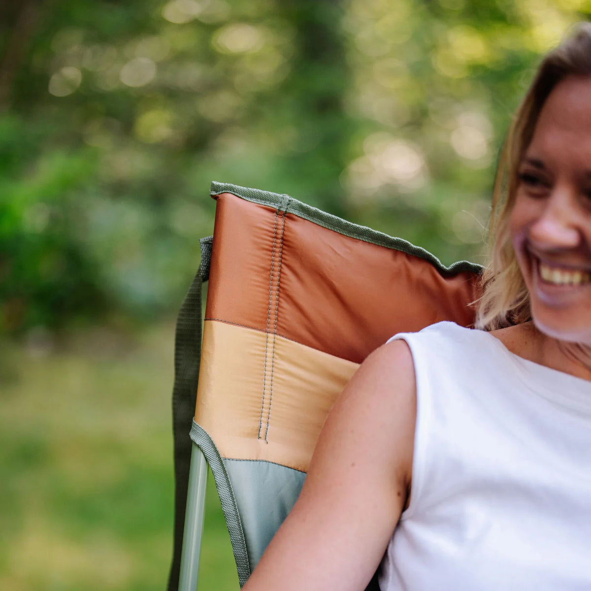 Close-up of a woman smiling while seated in an olive Comfort Pro Insulated Rocker.
