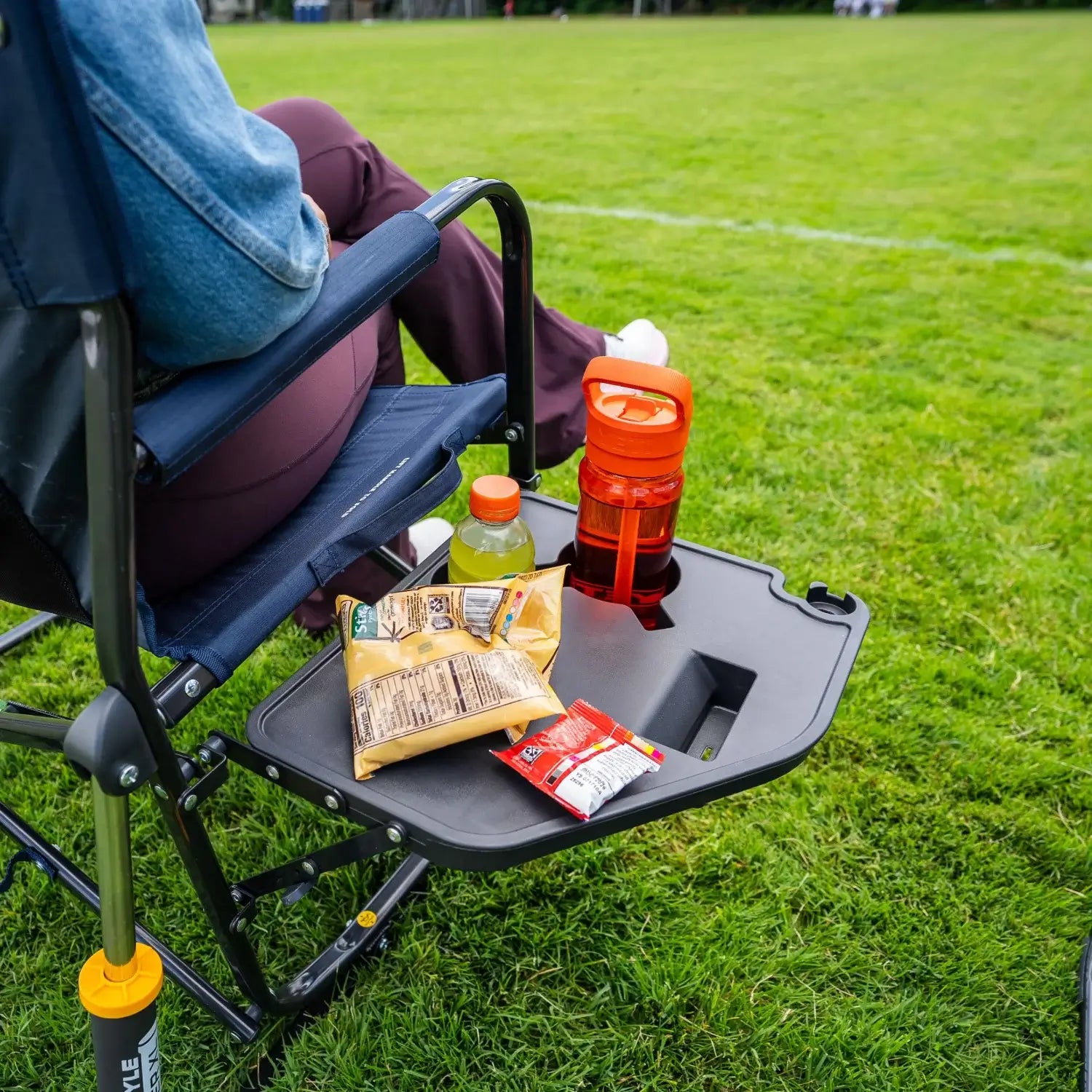 Close-up of the Side Table on an indigo Freestyle Rocker XL, holding snacks and drinks beside a seated person.