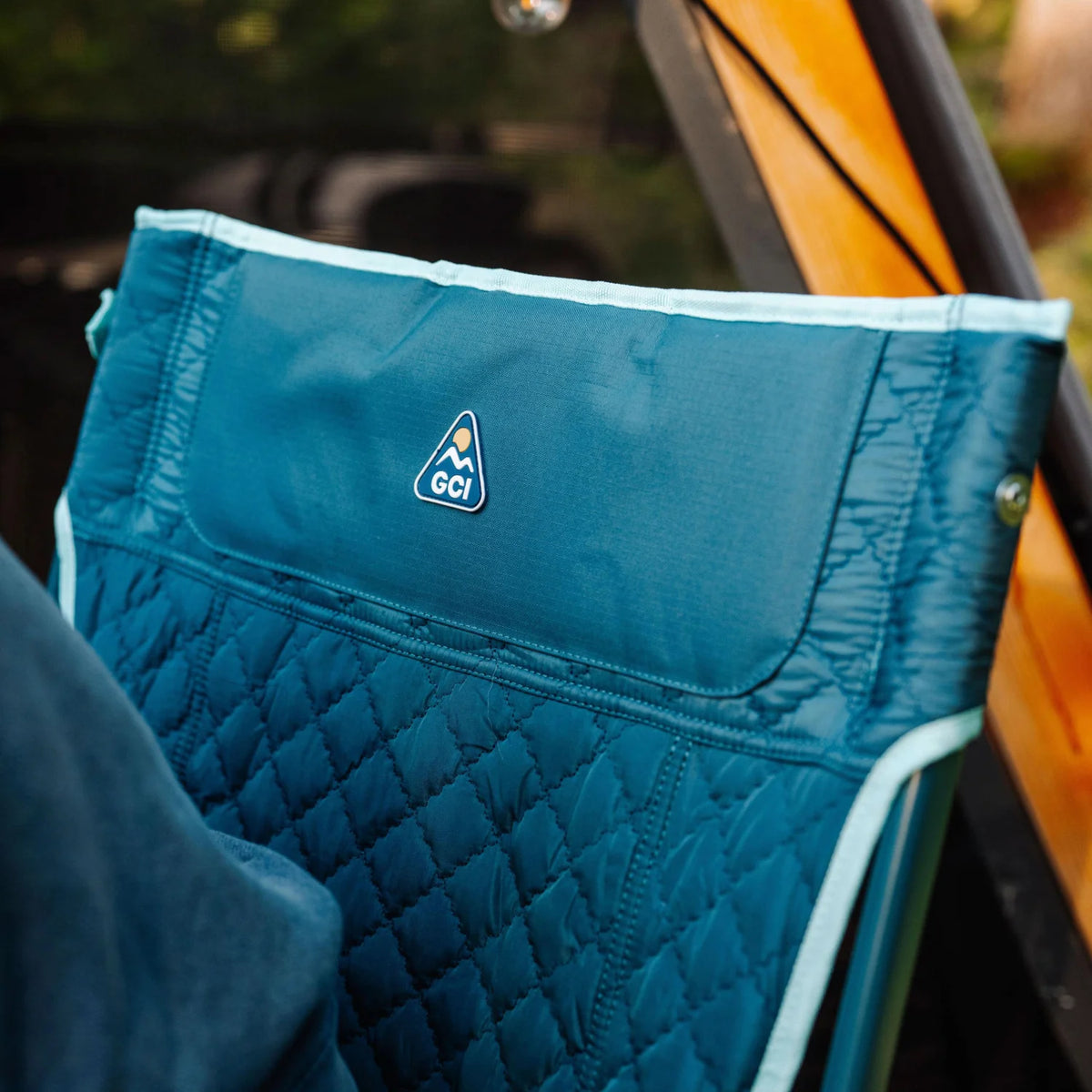 Close-up of the quilted backrest on a teal Kickback Insulated Rocker, with GCI logo shown on the upper panel.