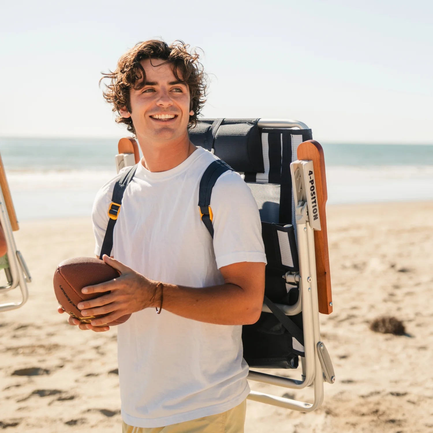 Man carrying TidalDrift indigo stripe backpack beach chair with padded shoulder straps on the beach.
