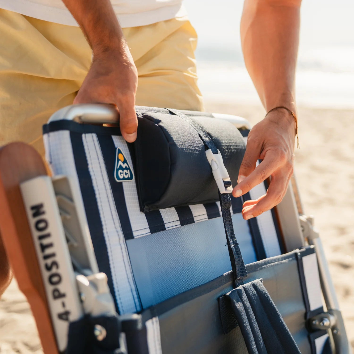 Adjusting the shoulder strap buckle on the TidalDrift backpack beach chair for easy carrying.