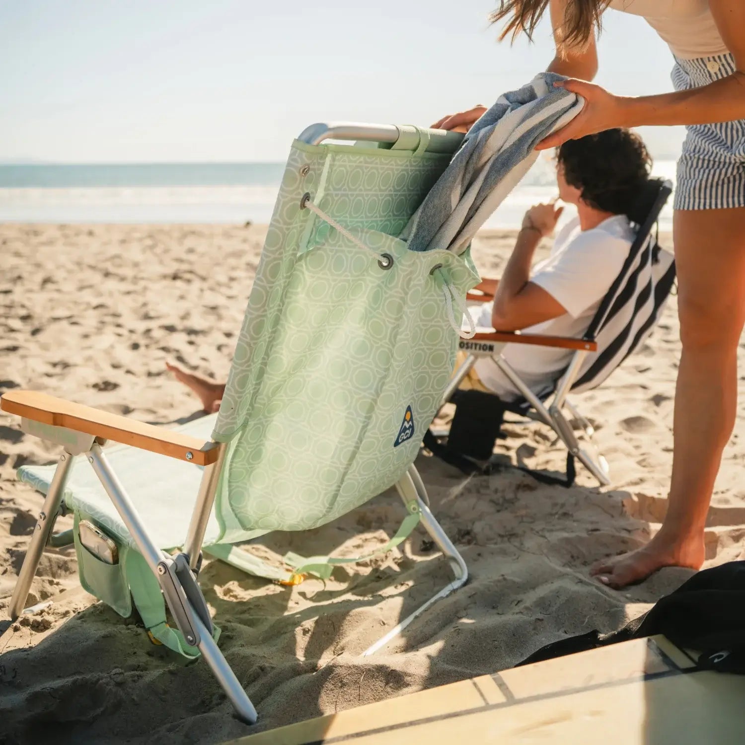 Tucking a towel into the back pocket of the TidalDrift pastel green mosaic backpack beach chair.