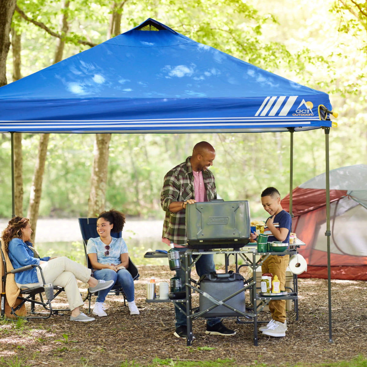 A family grilling underneath a Levrup Canopy while cooking on a Master Cook Station. 