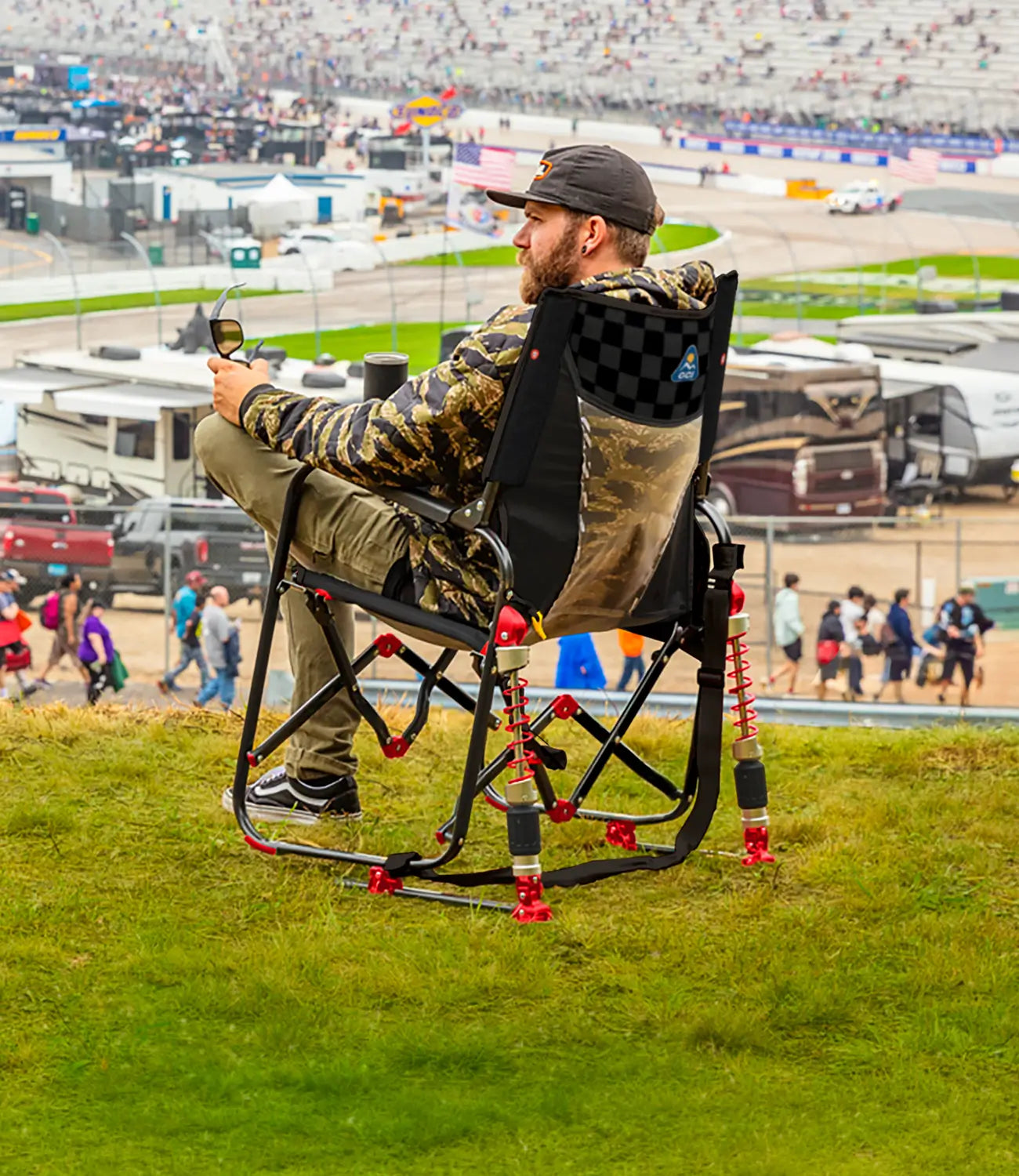 A man watching a racetrack while sitting in a NASCAR themed Adjustable Rocker. 
