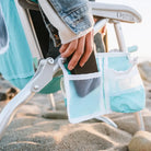 Close-up of a hand placing a phone into the mesh side pocket of a Bi-Fold Beach Chair with "4-POSITION" text on the arm.