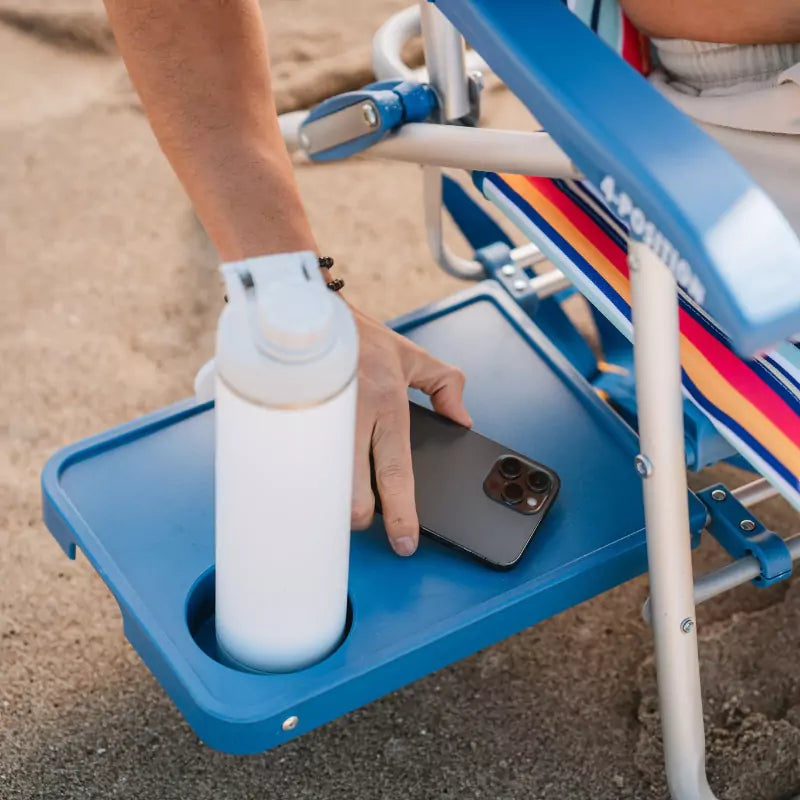 Close-up of a built-in tray on a Big Surf chair holding a phone and water bottle.