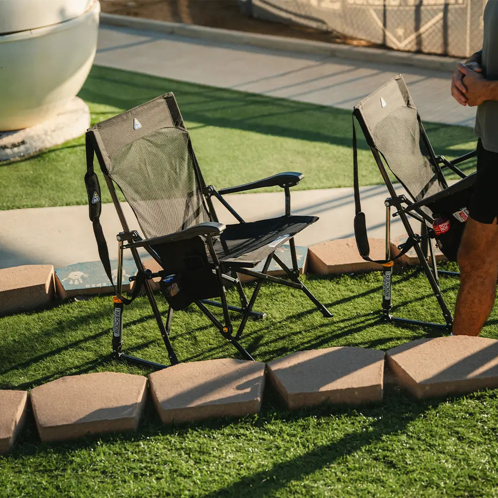 Two Black Breeze Rockers placed side by side on grass near the field.