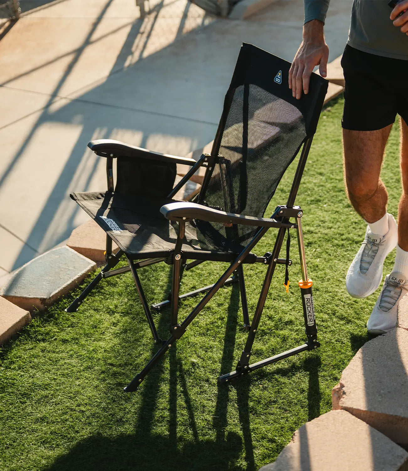 A man touching the backrest of a black Breeze Rocker chair. 