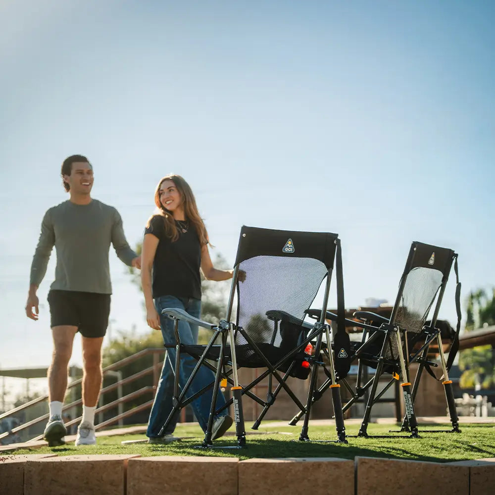 Two Black Breeze Rockers set up side by side on grass as people walk toward the seating area.