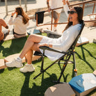 Person relaxing in the Black Breeze Rocker beside a baseball field on a sunny day.