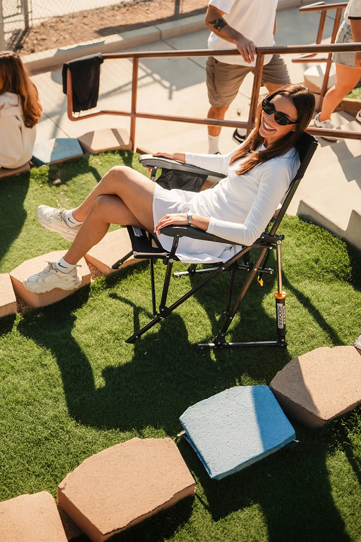 A woman smiling while sitting in a Breezerocker chair at a baseball game. 